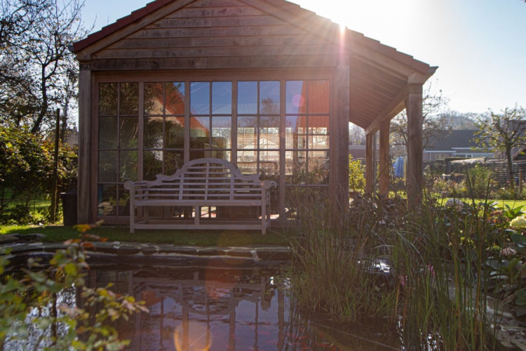 Landelijke tuin met kleine vijver en eiken bijgebouw